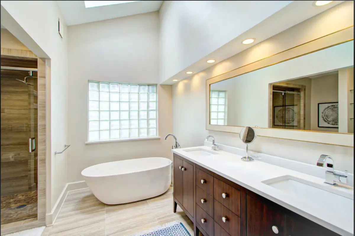 A modern bathroom featuring a freestanding bathtub, double vanity, and large mirror. The decor is calm and rejuvenating, inviting relaxation and pampering after an active day.