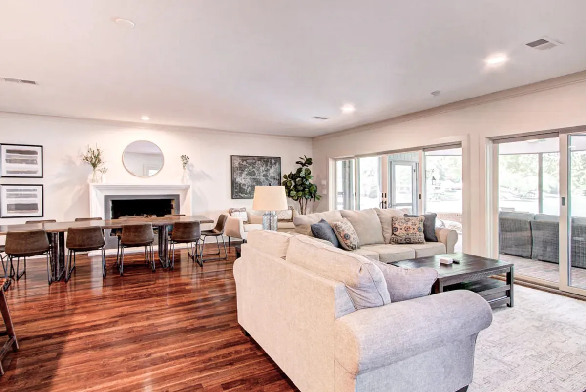 A cozy seating arrangement featuring a plush sofa, decorative pillows, a welcoming fireplace, and a dining table bathed in natural light. The space suggests intimate family gatherings and relaxed socialization, with an inviting atmosphere.