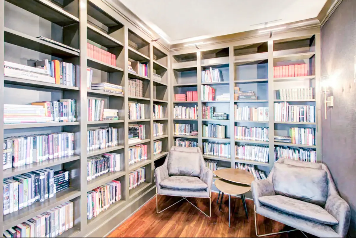A tranquil reading nook with bookshelves, plush seating, and a table set for quiet moments. The mood is serene and intellectual, suggesting a perfect spot for reading, studying, or enjoying a board game in peace.