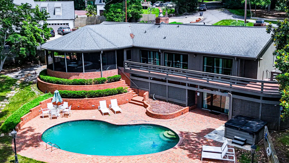 An inviting pool area framed by a landscaped garden and plush outdoor seating. The sparkling pool is the centerpiece, with a patio that invites morning coffee, sunbathing, or evening gatherings. The view hints at the proximity to the lake, blending relaxation with scenic outdoor beauty.