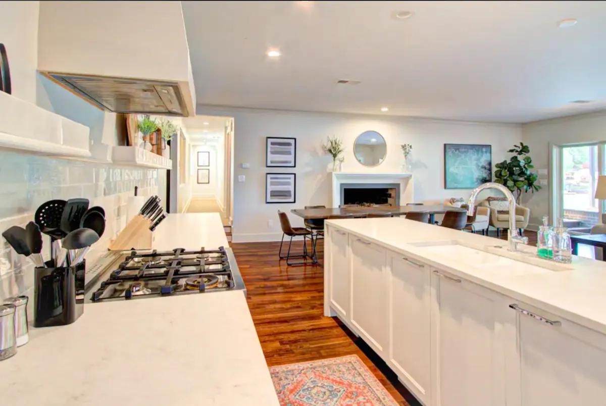 A stylish modern kitchen with a prominent island, stainless steel appliances, and an adjacent dining area. The space exudes warmth and sophistication, ideal for cooking, entertaining, and hosting family or friends.